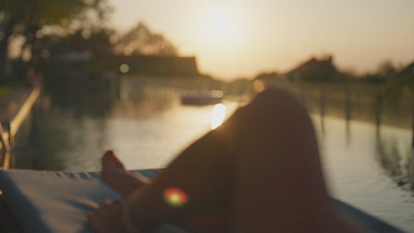 Video of Person Relaxing in Woven Chaise Lounge Next to a Pool During Sunset